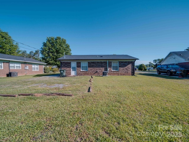 rear view of property featuring central air condition unit, a lawn, and brick siding