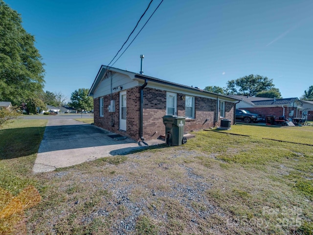 view of side of property with brick siding, a lawn, and central air condition unit
