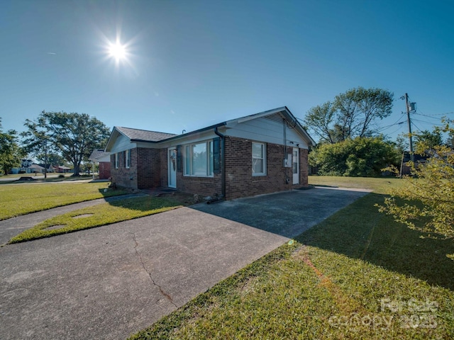 view of front of home with brick siding, driveway, and a front yard