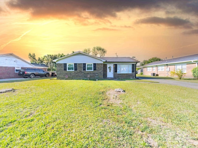 view of front of house with a lawn and brick siding