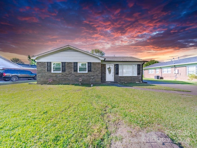 single story home with a front yard, brick siding, and central AC