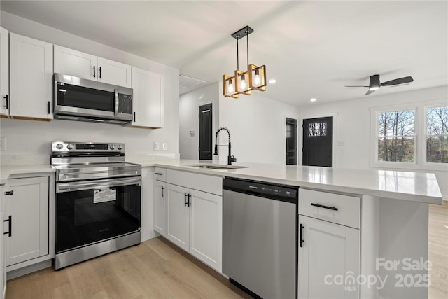 2120 Green Oak Dr, Shelby, NC 28152 - kitchen with appliances with stainless steel finishes, a sink, a peninsula, light wood-style flooring, and light countertops