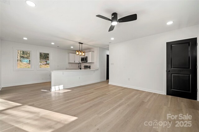 2120 Green Oak Dr, Shelby, NC 28152 - unfurnished living room featuring light wood-type flooring, recessed lighting, baseboards, a ceiling fan, and a sink