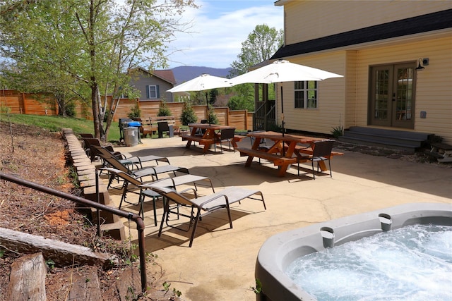 view of patio featuring french doors, a hot tub, fence, and outdoor dining space