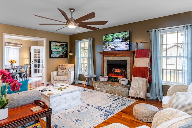 living area featuring ceiling fan, wood finished floors, a fireplace, and baseboards