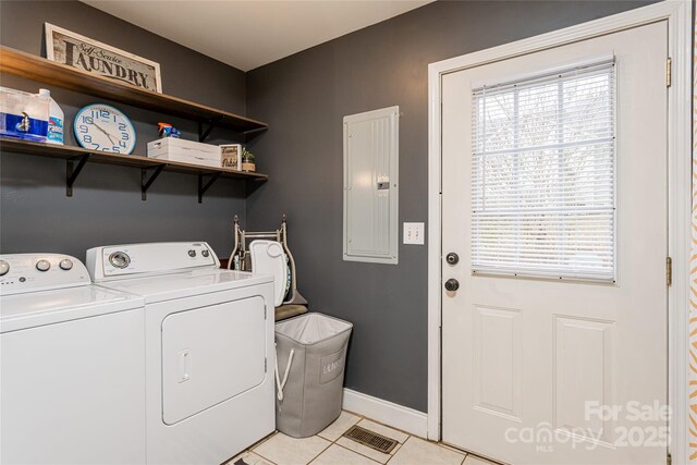 laundry area featuring electric panel, washing machine and clothes dryer, light tile patterned floors, and baseboards