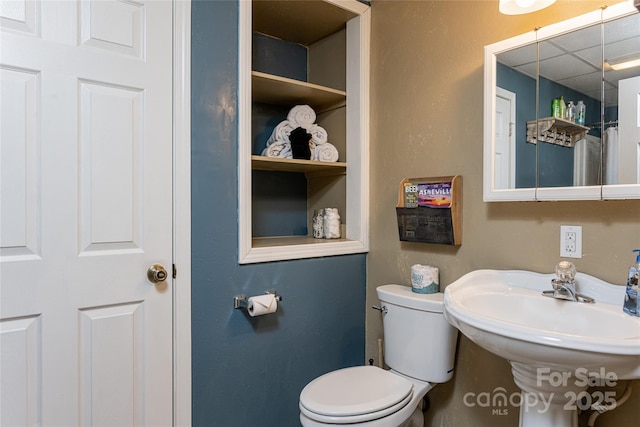 bathroom featuring toilet, a sink, and a drop ceiling