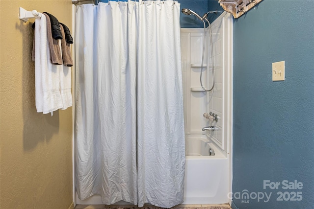 bathroom with shower / bath combination with curtain and a textured wall