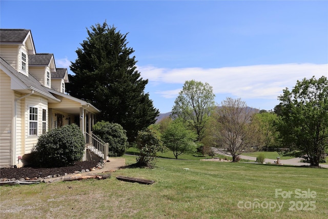 view of grassy yard with a porch and stairway