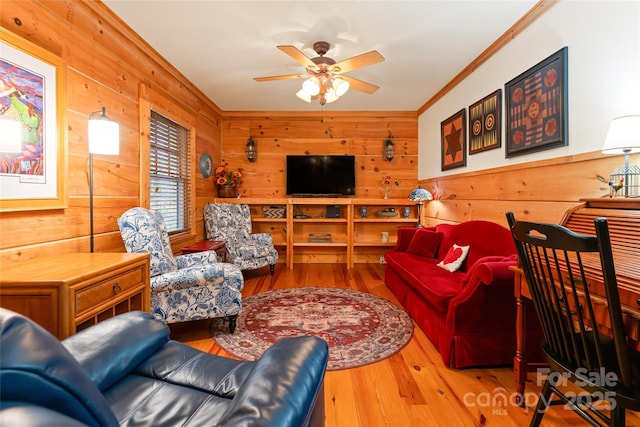 living room featuring ornamental molding, wood walls, ceiling fan, and wood finished floors
