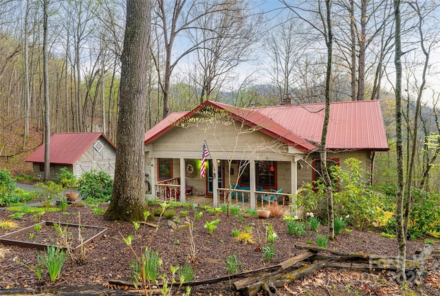 view of front of property with metal roof, a chimney, and a vegetable garden