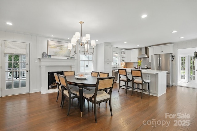 dining room with recessed lighting, dark wood-style flooring, a notable chandelier, and a fireplace