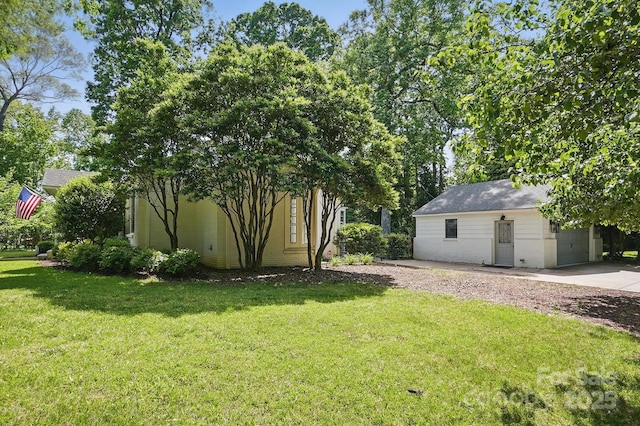 view of yard featuring a garage, an outbuilding, and driveway
