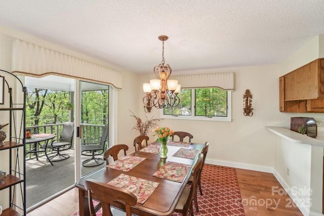 dining area with baseboards, wood finished floors, a textured ceiling, and a chandelier
