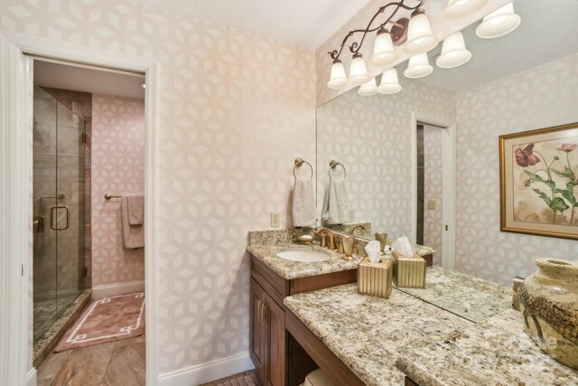 full bath with a shower stall, vanity, and wallpapered walls