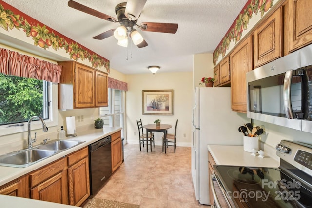 kitchen featuring stainless steel appliances, brown cabinets, light countertops, and a sink