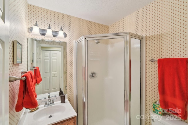 bathroom featuring a shower stall, vanity, a textured ceiling, and wallpapered walls