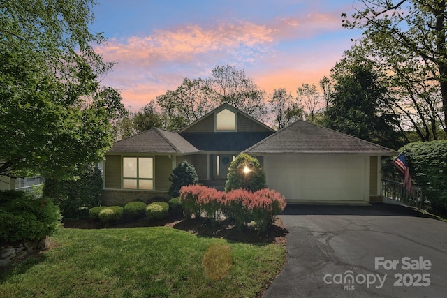 view of front of house featuring a front yard, roof with shingles, a garage, and aphalt driveway