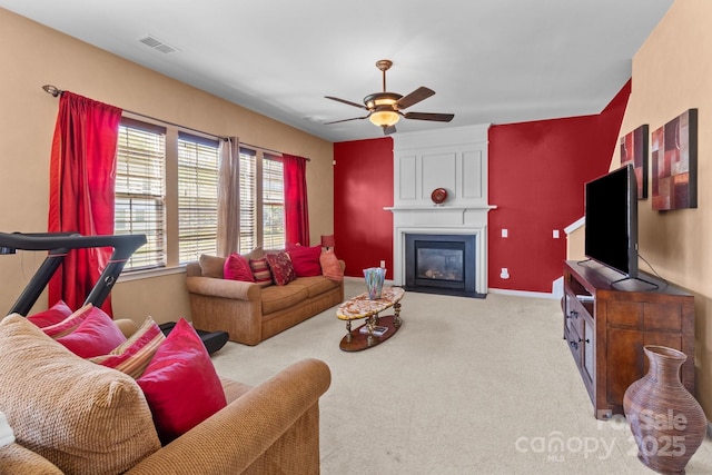 living area featuring visible vents, carpet, baseboards, a fireplace, and ceiling fan