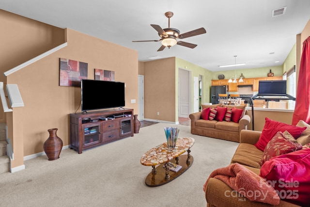 living area with baseboards, visible vents, ceiling fan, and carpet floors