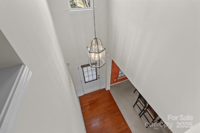 entryway featuring wood finished floors, a towering ceiling, and a chandelier