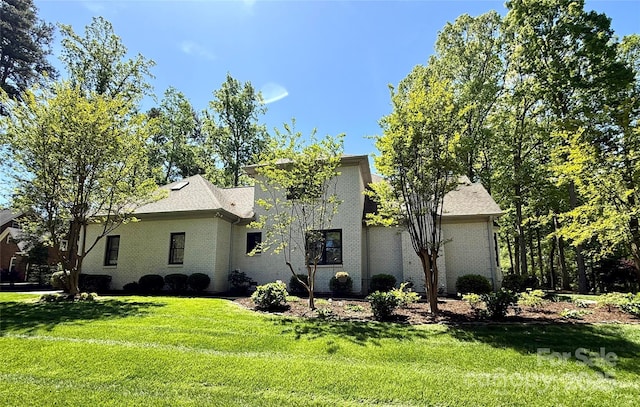 back of property featuring a lawn and brick siding