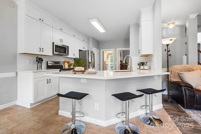 1214 Foxfield Rd, Waxhaw, NC 28173 - kitchen featuring appliances with stainless steel finishes, a breakfast bar area, decorative backsplash, and white cabinetry