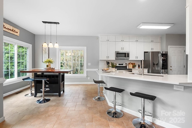 1214 Foxfield Rd, Waxhaw, NC 28173 - kitchen featuring appliances with stainless steel finishes, baseboards, a breakfast bar area, white cabinets, and light countertops