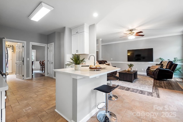 1214 Foxfield Rd, Waxhaw, NC 28173 - kitchen with a breakfast bar area, white cabinetry, light countertops, a sink, and a ceiling fan
