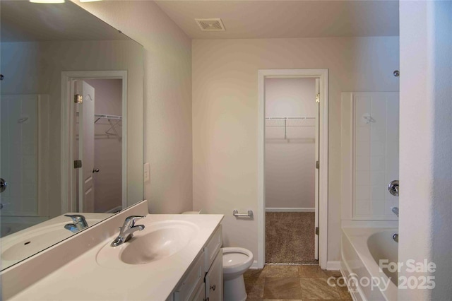 full bathroom with vanity, a spacious closet, toilet, a tub to relax in, and visible vents