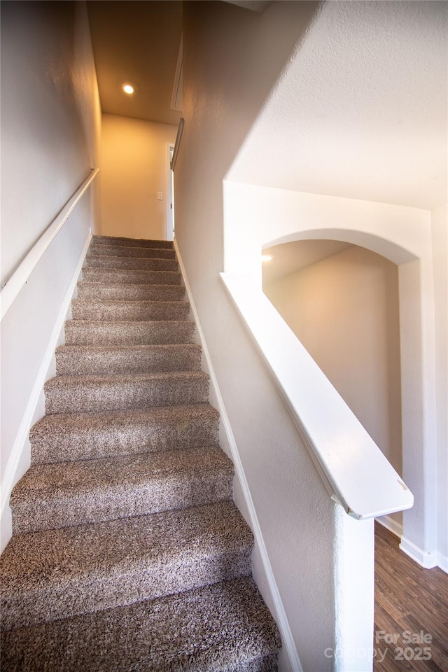 stairway with baseboards, wood finished floors, and recessed lighting