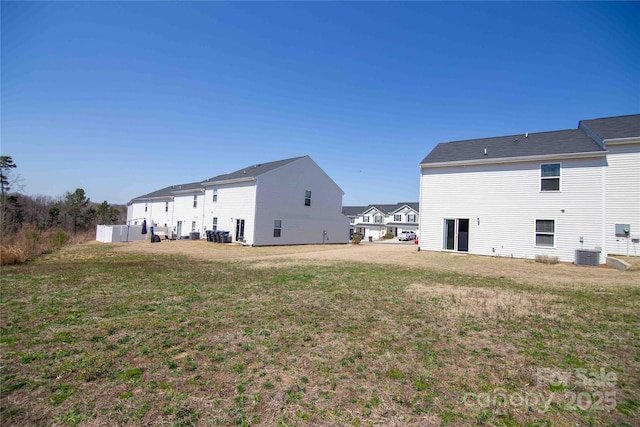 rear view of property featuring central AC unit and a lawn