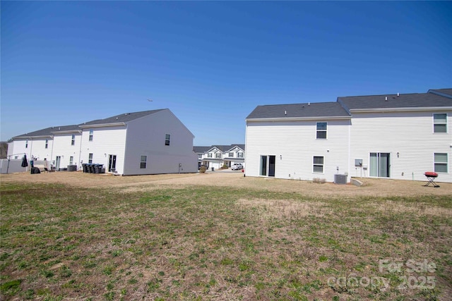 back of property featuring central air condition unit, a residential view, and a yard