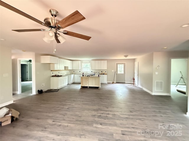 unfurnished living room with baseboards, wood finished floors, and a ceiling fan