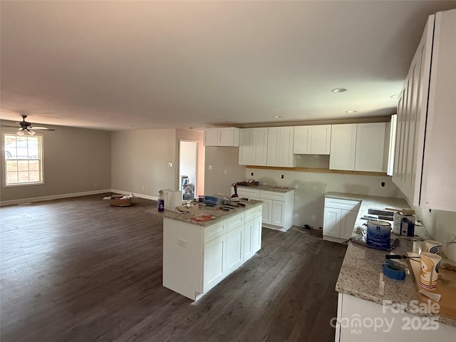 kitchen with dark wood-style floors, white cabinetry, a kitchen island with sink, light stone countertops, and recessed lighting
