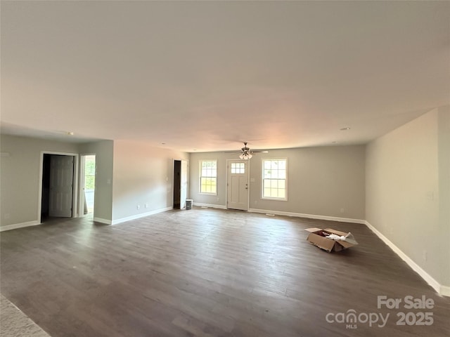 unfurnished living room featuring dark wood-style flooring, baseboards, and a ceiling fan
