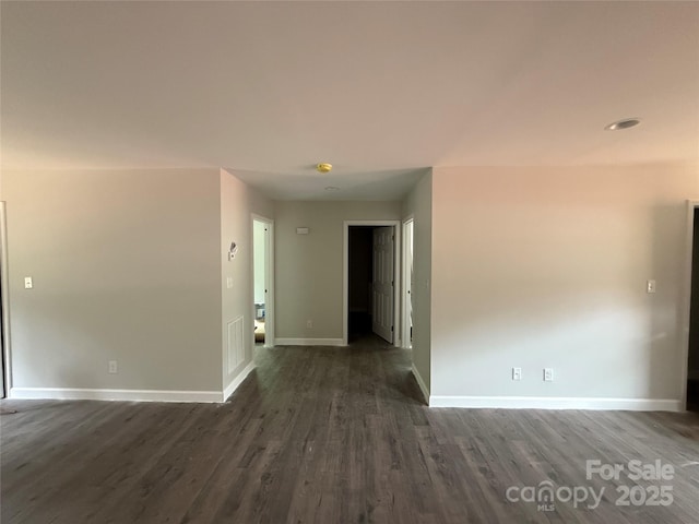 empty room featuring dark wood-style flooring and baseboards