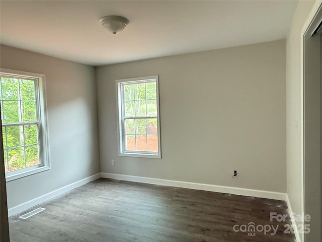 unfurnished room with healthy amount of natural light, baseboards, and wood finished floors