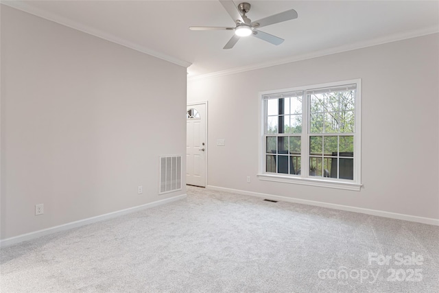 empty room featuring a ceiling fan, light colored carpet, baseboards, ornamental molding, and visible vents