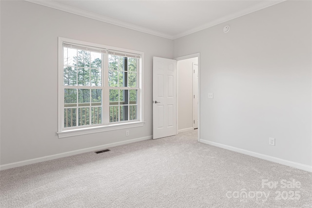 carpeted empty room featuring a wealth of natural light, visible vents, baseboards, and ornamental molding