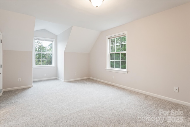 additional living space featuring vaulted ceiling, baseboards, and light carpet