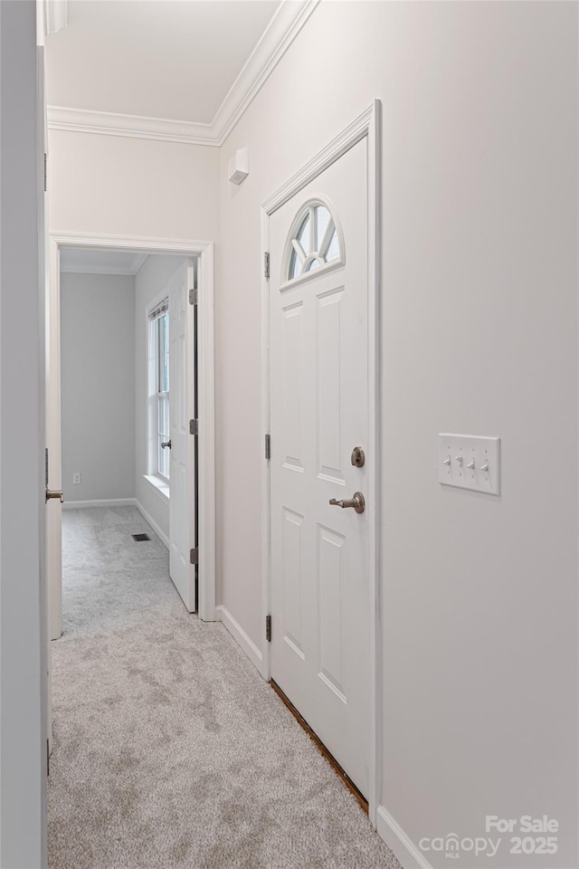 carpeted entryway featuring baseboards and ornamental molding