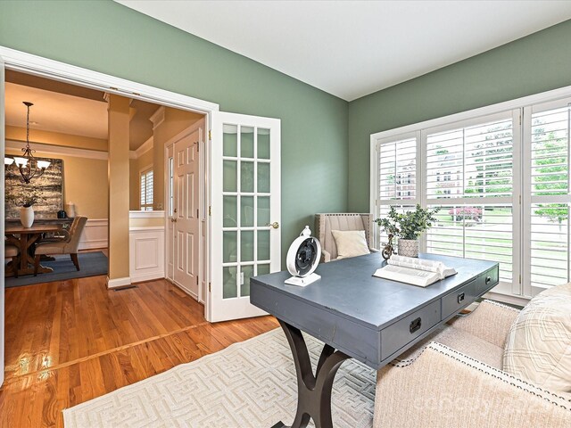 office area with a chandelier, healthy amount of natural light, and wood finished floors