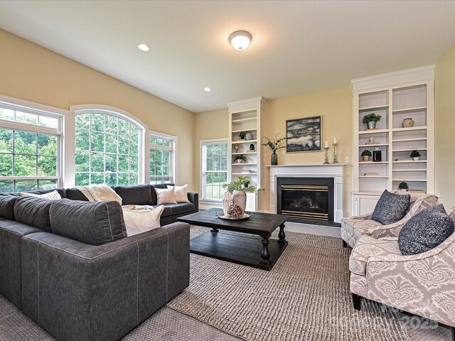 living area featuring a glass covered fireplace, carpet floors, and recessed lighting