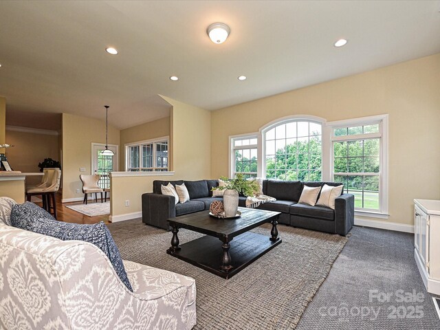 living area featuring baseboards, plenty of natural light, recessed lighting, and dark carpet