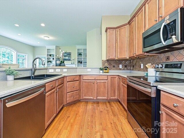 kitchen featuring stainless steel appliances, a sink, light countertops, light wood-style flooring, and recessed lighting