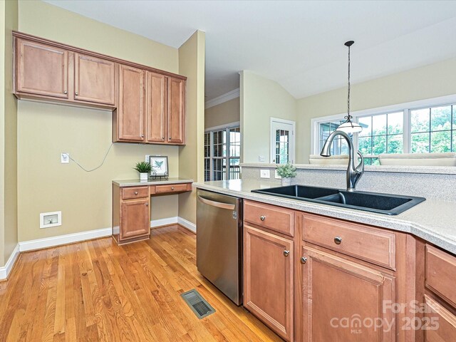kitchen featuring dishwasher, a sink, light countertops, light wood finished floors, and baseboards