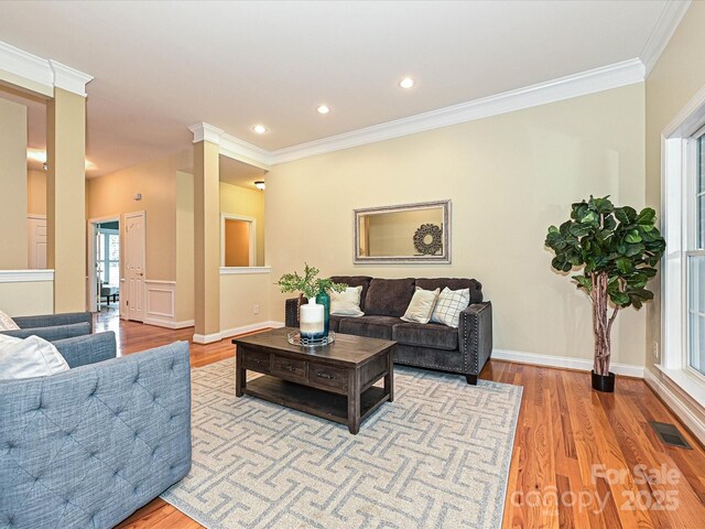 living area with wood finished floors, crown molding, recessed lighting, and baseboards
