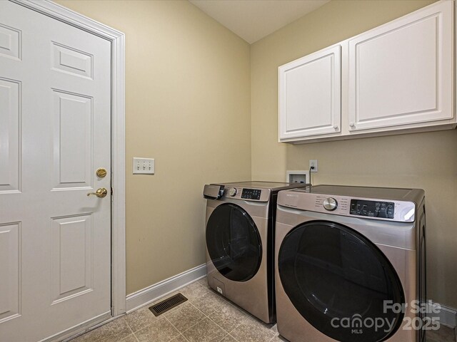 clothes washing area featuring baseboards, separate washer and dryer, and cabinet space