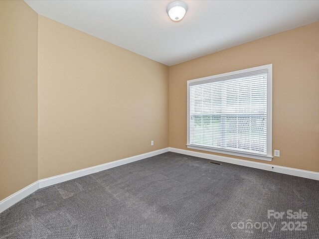 spare room with baseboards and dark carpet